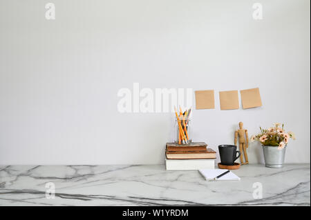 Marmortisch mit Büchern, Kaffee, Blumen, Stift und Zettel ein Büro Schreibtisch Konzept. Stockfoto