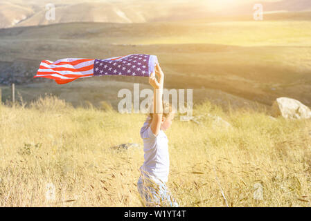 Amerikanische Flagge. Wenig patriotische Happy girl läuft mit amerikanischer Flagge schwenkten auf die Natur im Hintergrund. USA feiern 4. Juli. Stockfoto