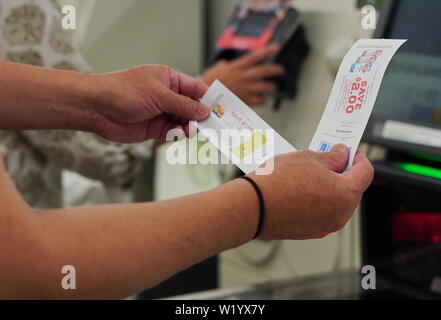 Cromwell, CT/USA - 16. Juni 2019: gebräunten Hände Coupons, die bis vor einem Self Checkout kiosk Stockfoto