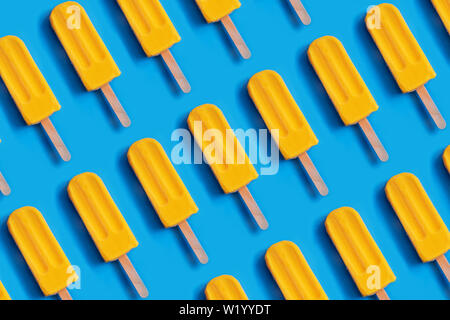 Muster aus hellen gelben mango Eis auf Blau pastell Hintergrund. Sommer Minimalismus Hintergrund. Stockfoto