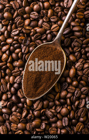 Löffel gemahlenen Kaffee auf einem Hintergrund mit gerösteten Kaffeebohnen Stockfoto