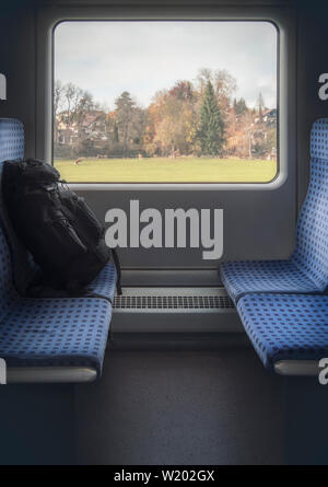 Vertikale Bild der Deutschen Bahn Innenraum mit blauen Stühlen, Gepäck und einen Herbst Blick auf das Fenster. Reisen in Deutschland mit einer Regionalbahn. Stockfoto