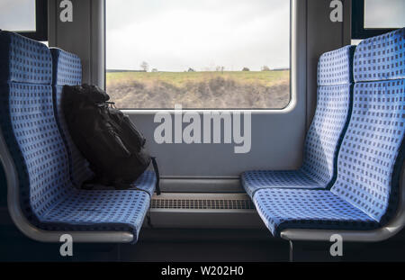 Gepäck auf dem blauen Stühlen eines Deutschen Regionalbahn und ein Fenster mit einem bewegungsbild. Reisen in Deutschland Konzept. Reisezeit. Stockfoto