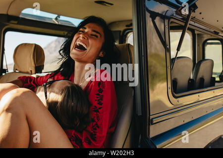 Glückliches junges Paar in Ihrem Auto sitzen und Lachen. Menschen, die auf der runden von seinem Lachen Freundin im Auto. Stockfoto