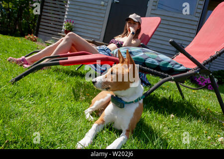 Basenji Hund und junge Frau Ruhe im Garten. Bei schönem Wetter Stockfoto