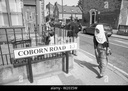 LONDON ENGLAND - 13. JULI 2013; Frau in hajib Spaziergänge rund um Straße Ecke Coborn Straße vorbei an der Schild in Schwarzweiß. Stockfoto