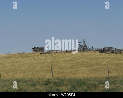 Weite Einstellung auf das Ackerland mit verfallenen Bauernhof Ausrüstung und Strukturen eine 1880s Stadt in South Dakota. Stockfoto