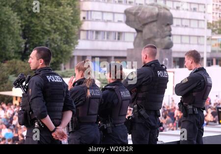 04 Juli 2019, Sachsen, Chemnitz: Polizisten stehen am Rande des Festivals "Kosmos Chemnitz - Wir bleiben mehr" an der Karl-Marx-Monument. Mit dem Festival, ein neues Zeichen für eine friedliche, weltoffene Gesellschaft gesetzt werden soll. Foto: Sebastian Willnow/dpa-Zentralbild/dpa Stockfoto