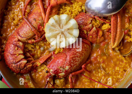 Nahaufnahme der cremigen Reis mit Hummer, Muscheln und anderen Meeresfrüchten. In paellera vorgestellt. Stockfoto