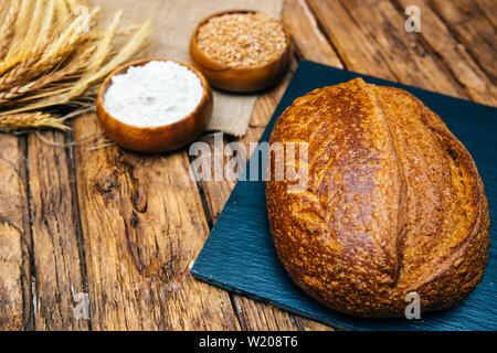 Sortiment von gebackenen frischen verschiedenen Roggen, Brot oder Vollkorn Brot, Weizen Ohr oder Spike und Mehl auf Holzbrett Tabelle. Bäckerei Konzept Bild. Stockfoto