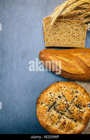 Sortiment von gebackenen frischen verschiedenen Roggen, Brot oder Vollkorn Brot, Weizen Ohr oder Spike und Mehl auf Holzbrett Tabelle. Bäckerei Konzept Bild. Stockfoto