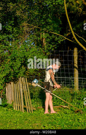 Mann mit einem STRIMMER, Gras und Unkraut im Garten zu schneiden Ungarn Zala county Stockfoto