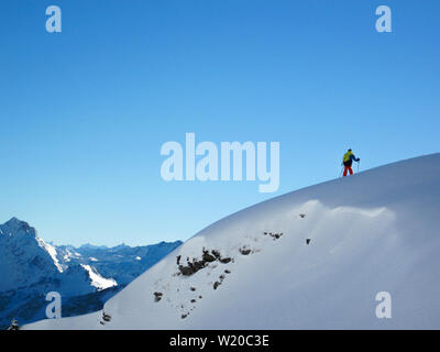 Cliff unter Schnee vor einem Berg Panorama im Winter in den österreichischen Alpen, mit einem Skifahrer auf. Stockfoto