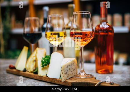 Gläser Wein und Käse. Sortiment oder verschiedene Art von Käse, Wein, Gläser und Flaschen auf dem Tisch im Restaurant. Rot, gelb und rosa Wein. Stockfoto