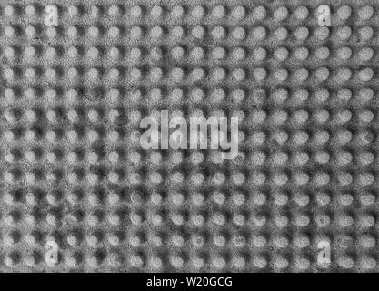 Nahaufnahme einer Verwitterten und verblasste Gummimatte mit Knöpfe in Schwarz und Weiß. Abstrakte hochauflösende Full Frame strukturierten Hintergrund. Stockfoto