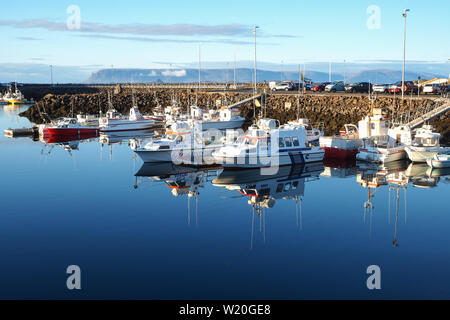 Boote im Hafen von Keflavik, Island, mit perfekter Reflexionen in das klare blaue Wasser, blauer Himmel und die Berge im Hintergrund Stockfoto
