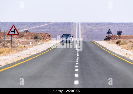 Weiß Toyoya Hilux Pick-up Truck entlang einer sehr gerade und lange asphaltierte Straße durch die Kalahari Wüste, Namibia fahren Stockfoto