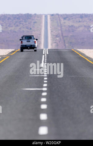 Weiß Toyoya Hilux Pick-up Truck entlang einer sehr gerade und lange asphaltierte Straße durch die Kalahari Wüste, Namibia fahren Stockfoto