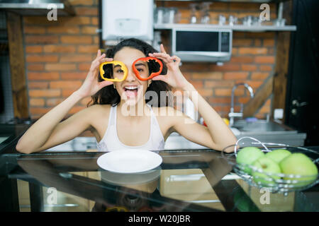 Lustige junge Frau, die Scheiben Paprika Stockfoto