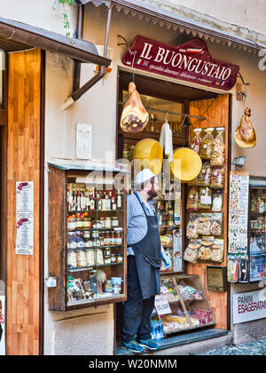 Lokale Anbieter wartet auf die Kunden am Eingang Ihres Geschäfts in das Dorf von Orta San Giulio, Ortasee Italien während einem Sommernachmittag Stockfoto