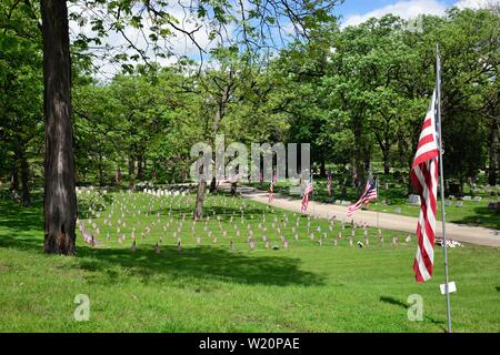 Elgin, Illinois, USA. Amerikanische Fahnen Linie Straßen auf einem Friedhof, wo kleinere Flagge Versionen der Grabstätte von Veteranen dot. Die Flags werden auf der Anzeige Stockfoto