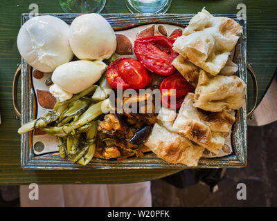 Schneidbrett aus Focaccia, Tomaten, Mozarella, Burrata und Antipasti. Stockfoto