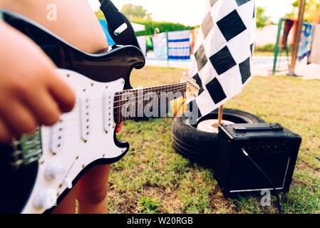 Detail einer E-Gitarre, die ein Kind in seinem Hinterhof auf seine Sommerferien statt. Stockfoto