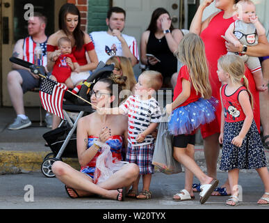 Bettendorf, Iowa, USA. 4. Juli 2019. Ashley Bearden, linke hält an zu ihrem 3-jährigen Sohn, wie er Wellen eine amerikanische Flagge während der muscatine 4. Juli Parade Parade am 2. Straße Donnerstag, Juli 4th, 2019. Credit: Kevin E. Schmidt/Viererkabel - Zeiten/ZUMA Draht/Alamy leben Nachrichten Stockfoto