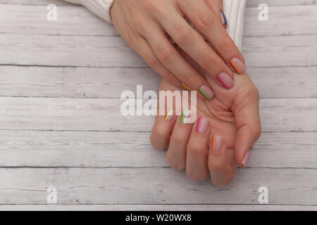 Bunte moderne Maniküre, Nail Design. Sommer Stimmung, auf Holz- Hintergrund. Stockfoto
