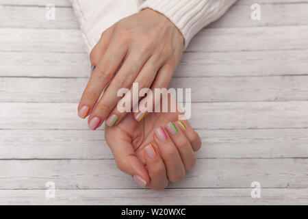 Bunte moderne Maniküre, Nail Design. Sommer Stimmung. Close-up auf Holz- Hintergrund. Stockfoto