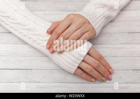 Bunte moderne Maniküre, Nail Design, Sommer Stimmung, die Hände in einer weißen Pullover Stockfoto