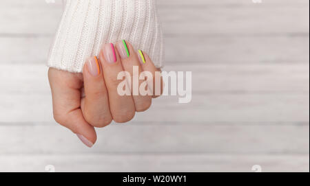 Schöne gepflegte Frau Hände mit farbigen Nägeln auf den hölzernen Hintergrund. Maniküre, Pediküre, Beauty Salon Konzept. Leeren Platz für Text oder Logo. Stockfoto