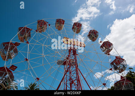 Rote Riesenrad gegen einen blau leuchtenden Himmel Sonne flare während der 2019 St Kilda Festival. Stockfoto