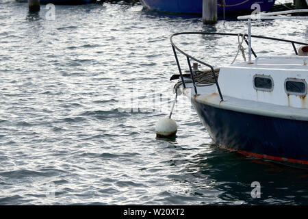 Eine private Freizeitaktivitäten Boot festgebunden an einem Weißen über Seil in einem Hafen Boje. Stockfoto