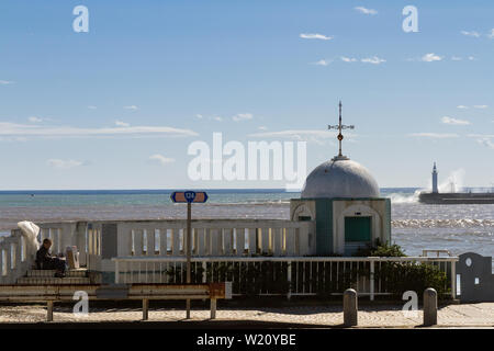 Ein obdachloser Mann sortiert sich über dem Strand in Enoshima nach dem Taifun Lan in Japan durch seine Habseligkeiten. Enoshima, Kanagawa, Japan. Stockfoto