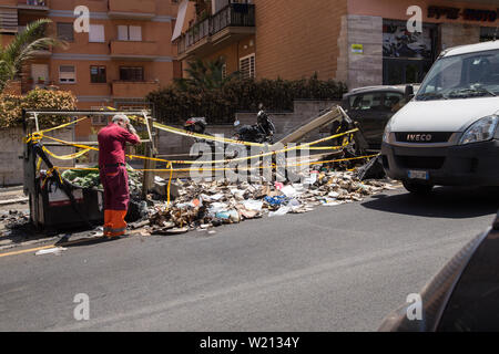 Roma, Italien. 03 Juli, 2019. Einige AMA Betreiber gehen Sie mit der Sammlung von Abfällen in eine Straße im Stadtteil von Rom Monteverde nach dem Brennen von einem Müllcontainer Credit: Matteo Nardone/Pacific Press/Alamy leben Nachrichten Stockfoto