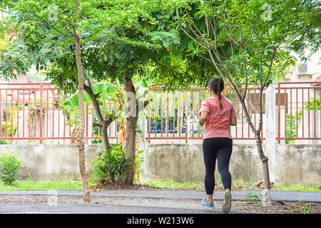 Asiatische Frauen sind Joggen im Park Hintergrund Baum. Stockfoto