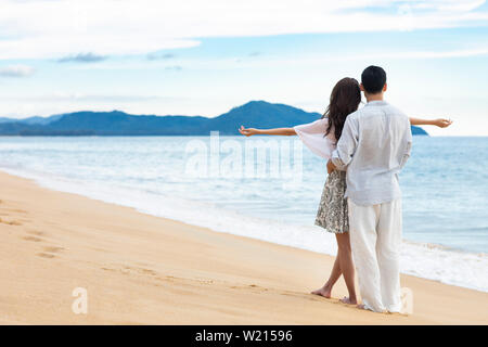 Glückliches junges Paar umarmt am Strand Stockfoto