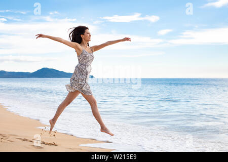 Glückliche junge Frau springen auf Strand Stockfoto