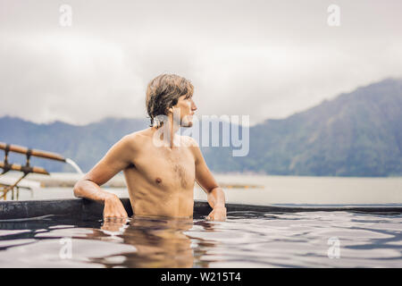 Geothermische Spa. Man Relaxen im heißen Pool. Junger Mann entspannt genießen, Baden in der Blauen Lagune, touristische Attraktion Stockfoto