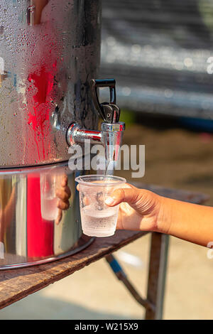 Hand junge Holding das Glas mit Wasser aus dem Kühler. Stockfoto