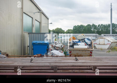 In einem Hinterhof gibt es Mülltonnen und Container mit Altmetall Stockfoto