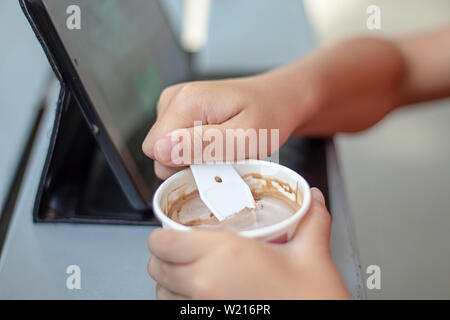 Hand junge halten sie die Löffel Eisportionierer in eine Tasse. Stockfoto