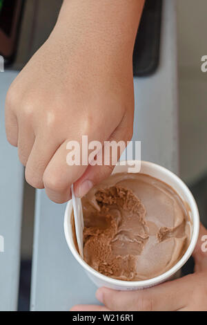 Hand junge halten sie die Löffel Eisportionierer in eine Tasse. Stockfoto