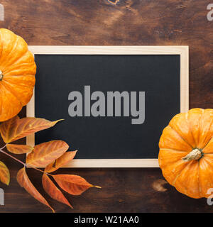 Herbst Schiefertafel Hintergrund mit Kürbissen, rote und gelbe Blätter. Ernte- und Herbstferien feier Konzept. Stockfoto