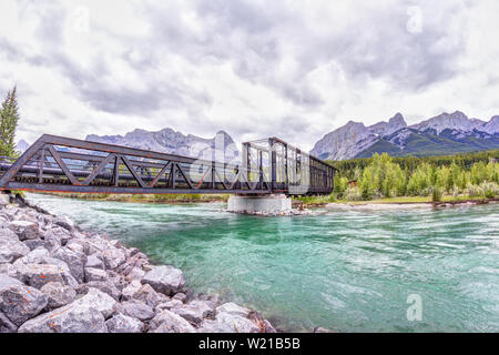 Historische Canmore Motor Brücke über den Bow River in der Kanadischen Rockies mit Ha Ling Peak und Mt Rundle im Hintergrund. Die Eisenbahnbrücke war bu Stockfoto