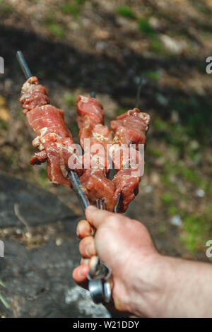 Mann hält in der Hand einen Spieß mit rohem Fleisch, Life Style. Stockfoto