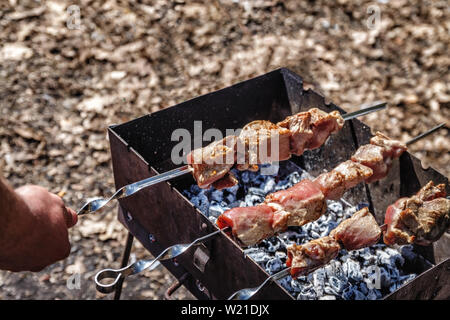 Mann hält in der Hand einen Spieß mit rohem Fleisch, Life Style. Stockfoto