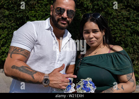 Paar bei sonnigem Wetter mit Blumen ihrer Kinder in der Hand Stockfoto