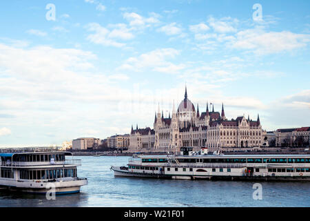 Stadtbild von Budapest mit hellen Parlament und Donau mit Brücke. Rosa und Lila Farben des Himmels spiegelt im Wasser während des Sonnenuntergangs. Stockfoto